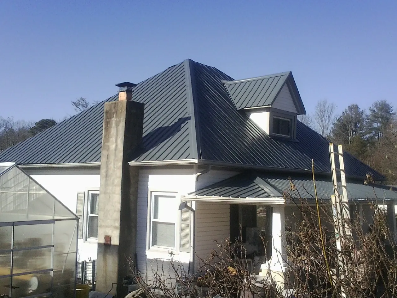 Dark blue standing seam metal roof on a white farmhouse with dormer — Slate & Tile Roof Repair by Roofing Brothers in New Vernon