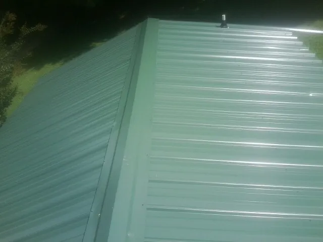 New green metal panels meeting at the ridge of a roof — Flat Roof Repair work by our crew in New Vernon