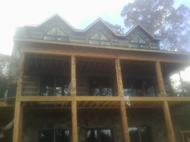 Dormers and porch framing on a large log home under construction — Roof Coating work by our crew in New Vernon