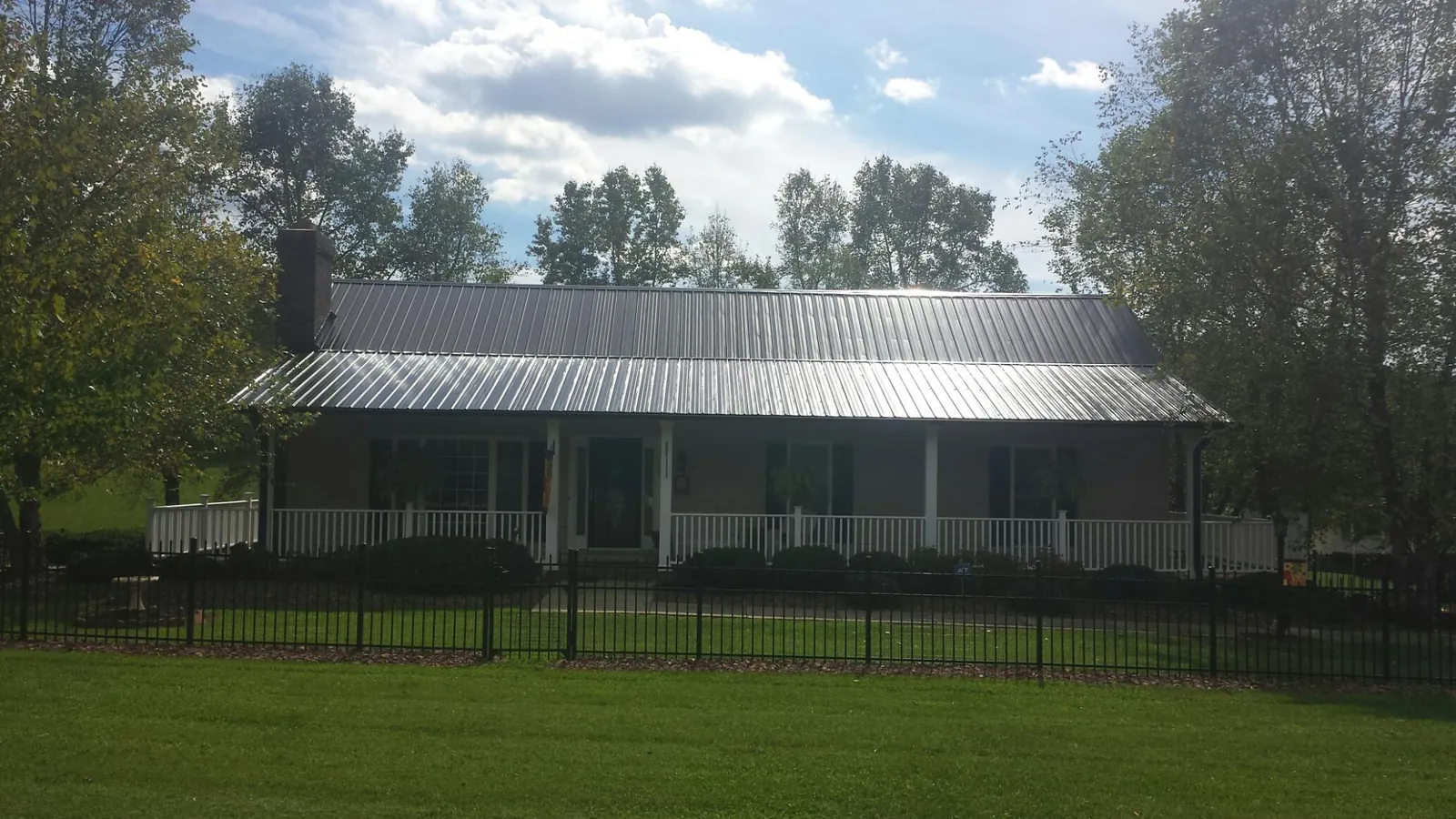 Gray metal roof on a brick ranch with a full width front porch — Gutter Guard Installation work by our crew in New Vernon