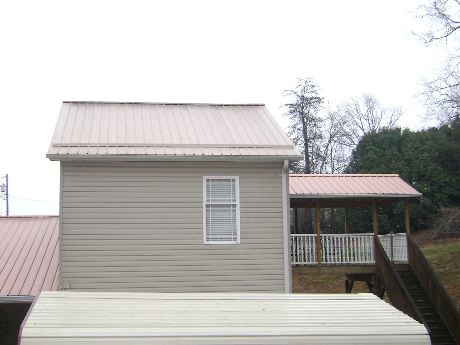 Tan metal roofs on a two story addition and attached porch, from a Roof Replacement job in New Vernon